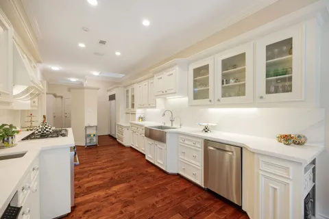 a kitchen with stainless steel appliances a stove a sink and white cabinets with wooden floor