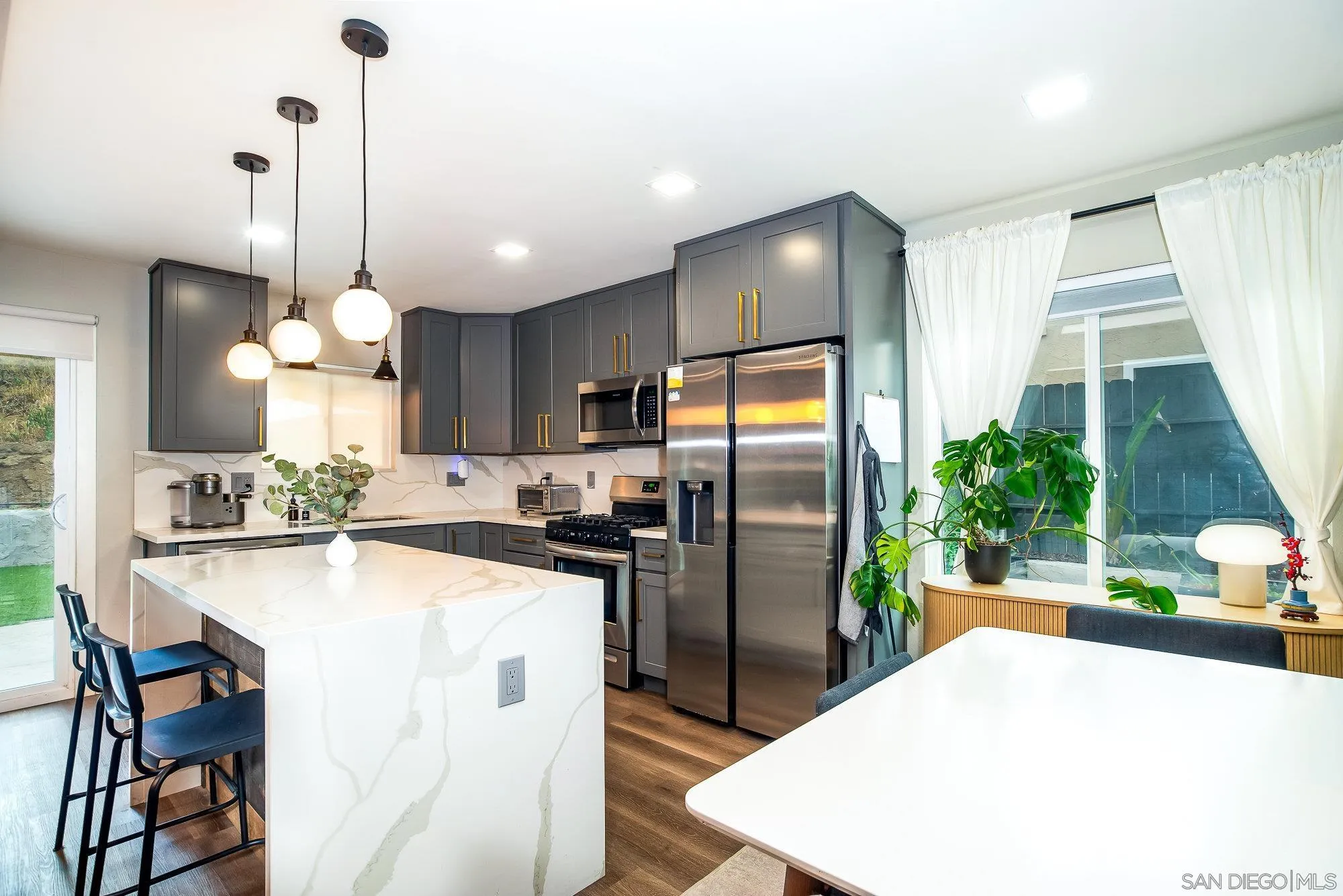 10753 Valor Place Santee, CA 92071 - Photo 12 of 24 a kitchen with stainless steel appliances kitchen island granite countertop a refrigerator a stove a sink a dining table and chairs with wooden floor