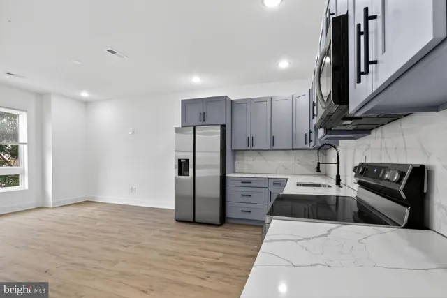 a kitchen with granite countertop a refrigerator and a stove top oven