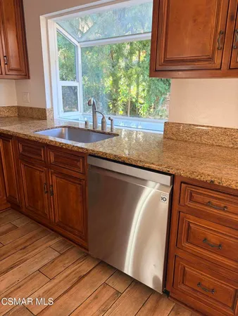 a kitchen with granite countertop wooden cabinets a sink and a window