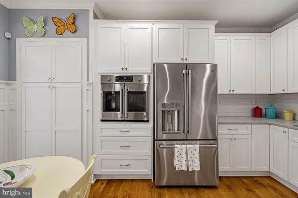 a kitchen with stainless steel appliances granite countertop a refrigerator a stove a sink dishwasher and white cabinets with wooden floor
