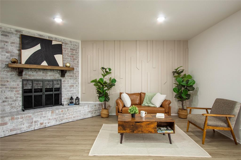 1205 Augusta Road Benbrook, TX 76126 - Photo 13 of 21 Living space featuring a whitewashed brick fireplace with a wood mantle, wood-finish flooring, recessed lighting, and a textured accent wall