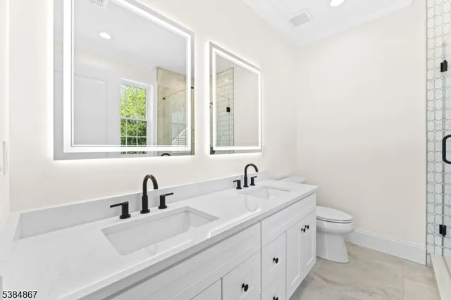 a bathroom with 2 sink toilet and a mirror