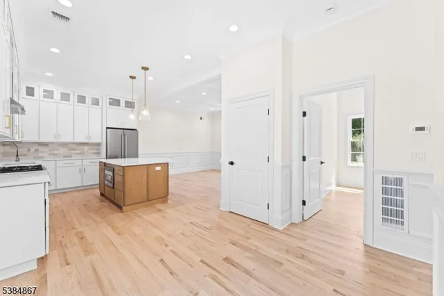a large kitchen with stainless steel appliances kitchen island wooden floors and white cabinets