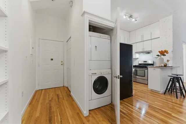 a hallway with washer and dryer with wooden floor
