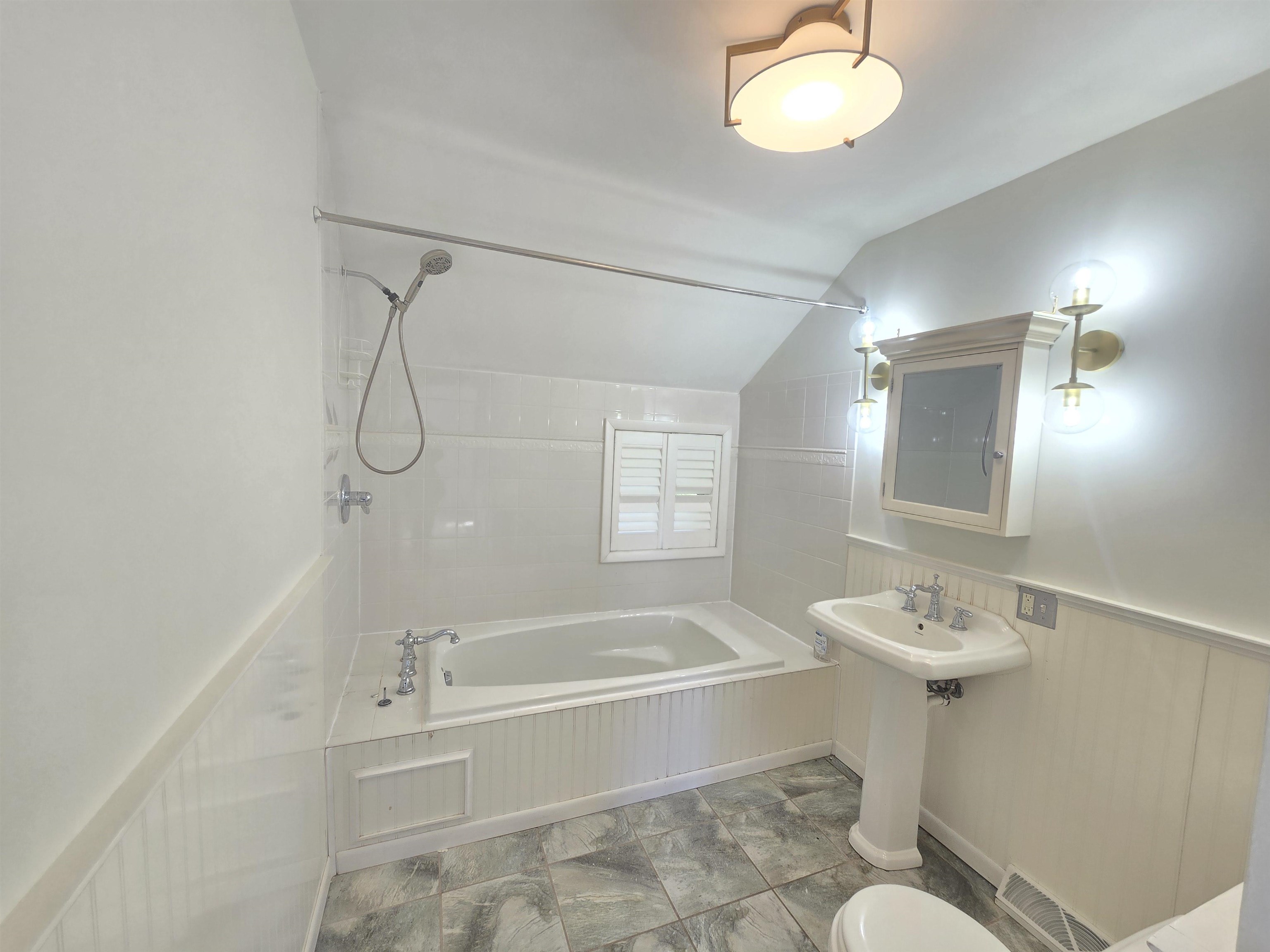 321 Rice Avenue Bayfield, WI 54814 - Photo 15 of 30 Bathroom featuring toilet, vaulted ceiling, and tiled shower / bath