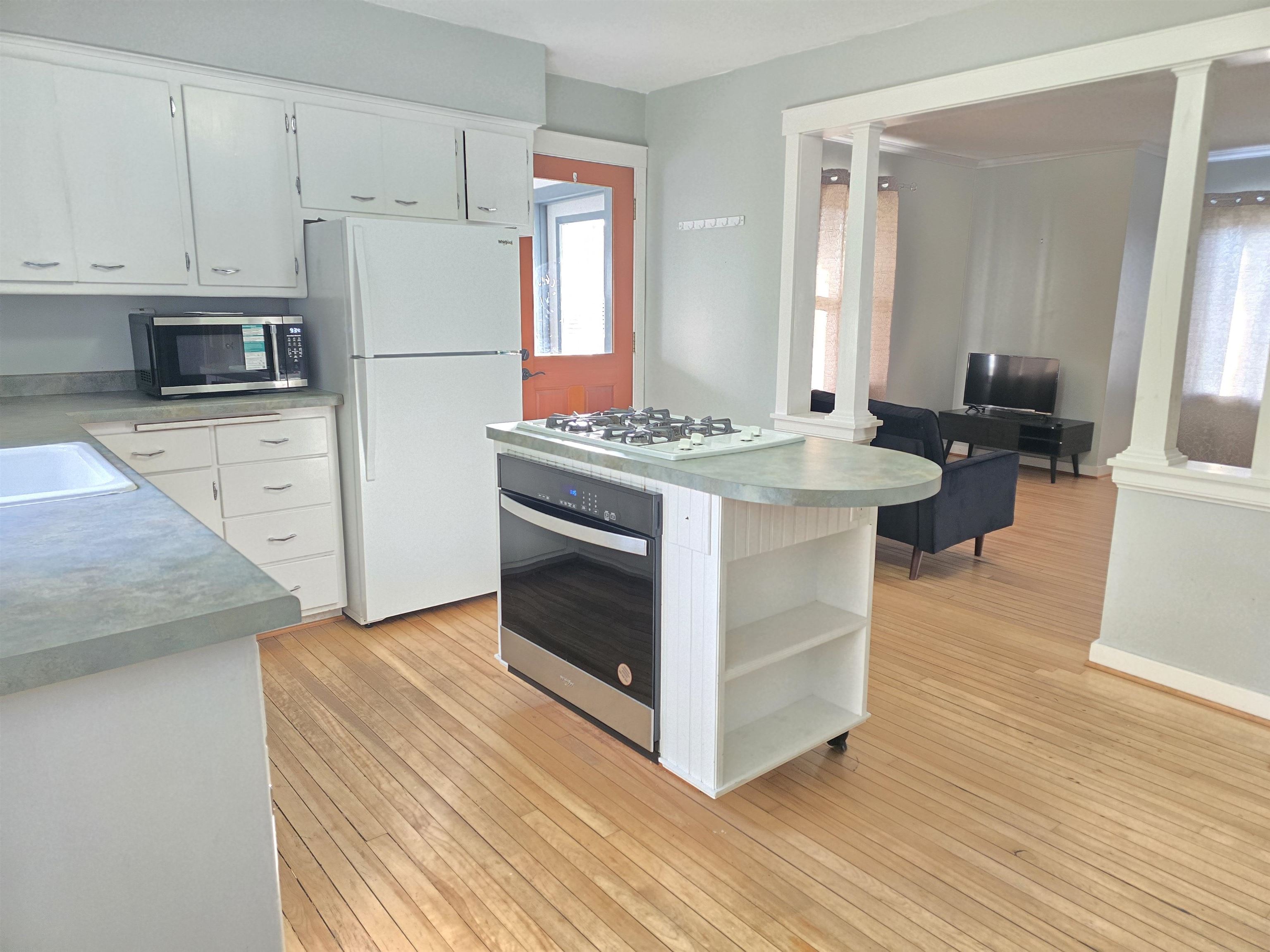 321 Rice Avenue Bayfield, WI 54814 - Photo 18 of 30 Kitchen featuring white cabinetry, ornate columns, appliances with stainless steel finishes, and light hardwood / wood-style flooring