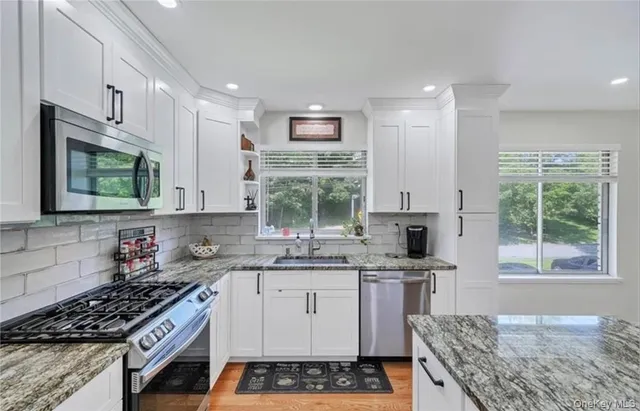 a kitchen with stainless steel appliances granite countertop a stove a sink and a microwave