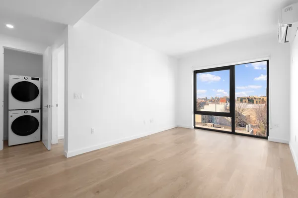 a view of a big room with wooden floor washing machine and dryer