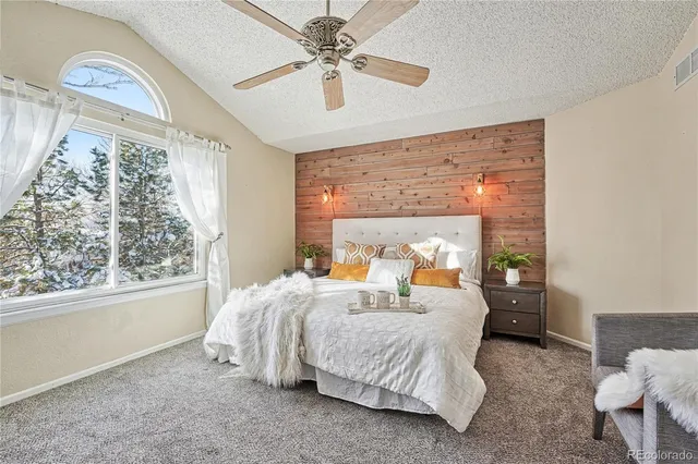 a bedroom with a large bed and a chandelier fan