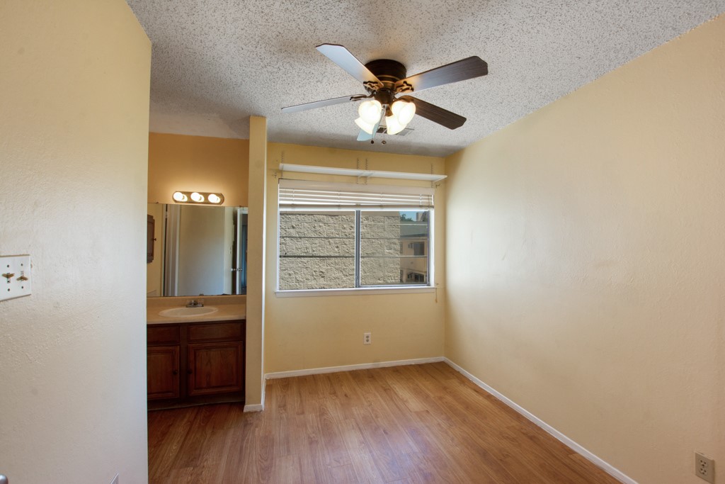 708 Graham Place, Unit 205 Austin, TX 78705 - Photo 3 of 11 an empty room with wooden floor fan and windows