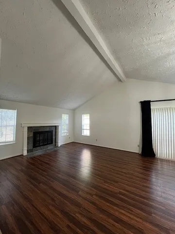 an empty room with wooden floor fireplace and windows