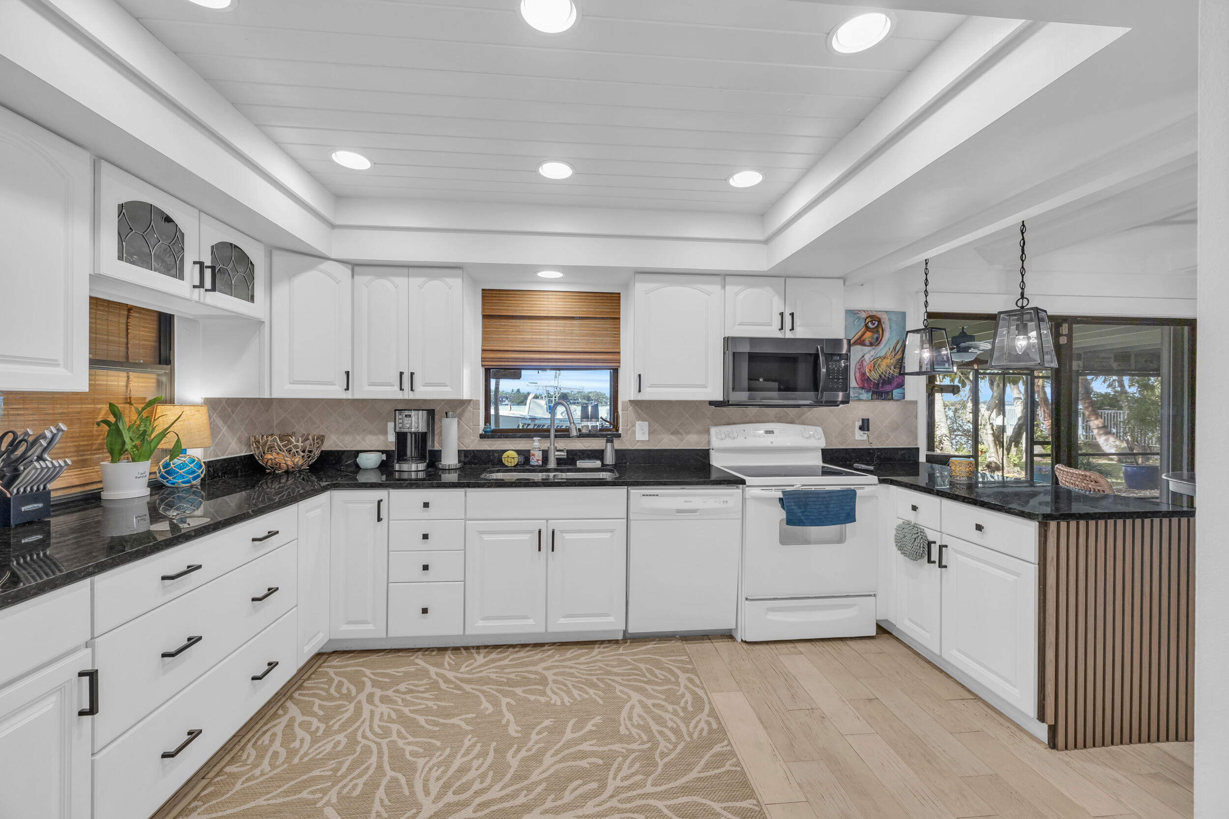 1305 Peninsular Road Jupiter, FL 33469 - Photo 14 of 46 a kitchen with granite countertop white cabinets and white appliances