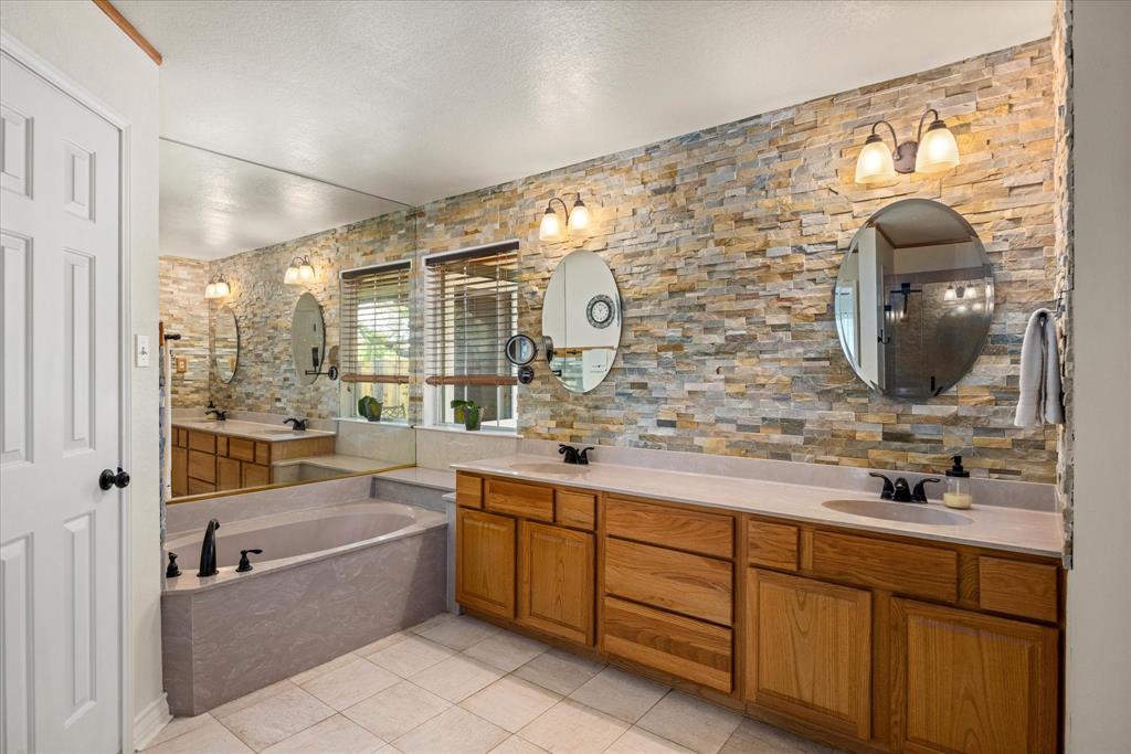 1311 Williamson Road Granbury, TX 76048 - Photo 27 of 40 a bathroom with a double vanity sink mirror and bathtub