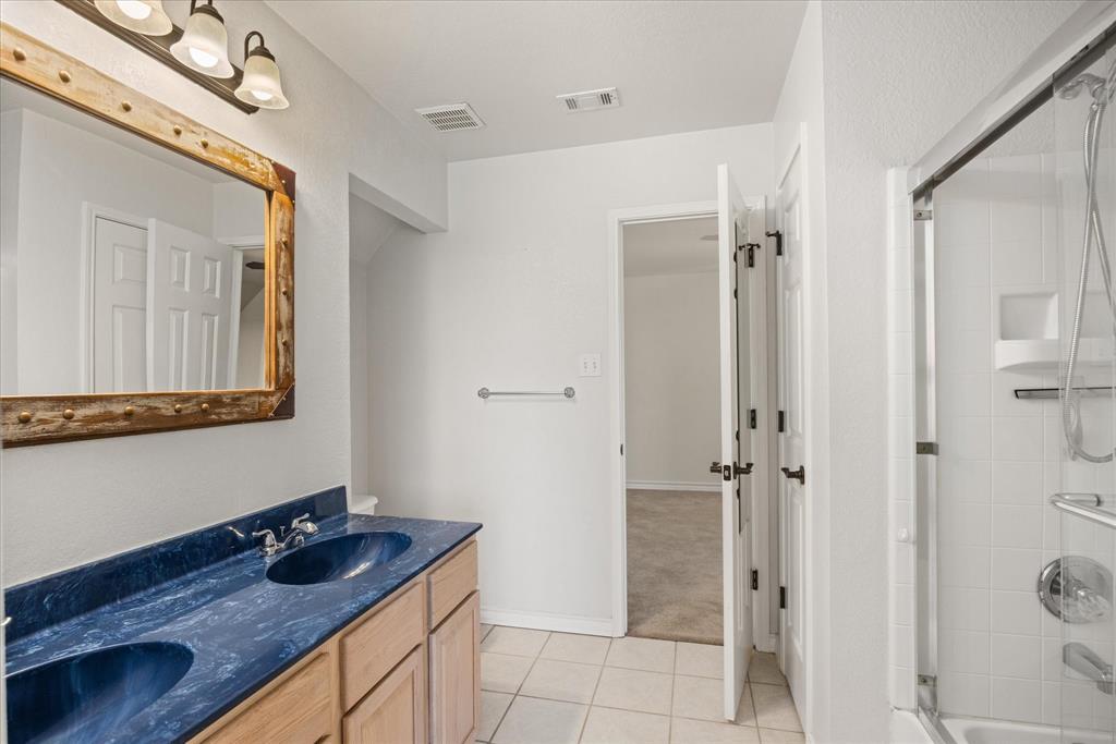 1311 Williamson Road Granbury, TX 76048 - Photo 32 of 40 a bathroom with a granite countertop sink a mirror and shower