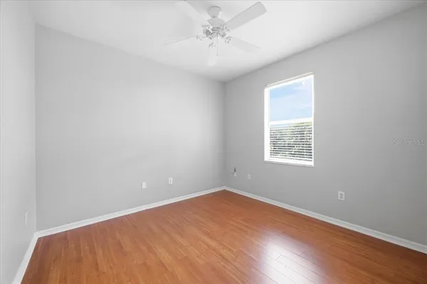 an empty room with a window and a ceiling fan