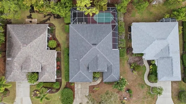 an aerial view of a house with swimming pool and large trees