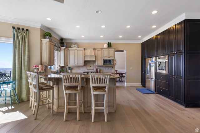 684 North Summit Way Alpine, UT 84004 - Photo 21 of 58 Kitchen featuring a peninsula, arched walkways, a breakfast bar area, light stone countertops, and stainless steel appliances