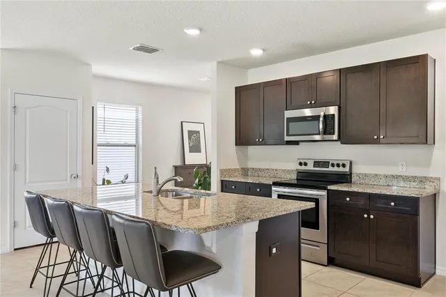 a kitchen with stainless steel appliances a dining table chairs refrigerator and microwave