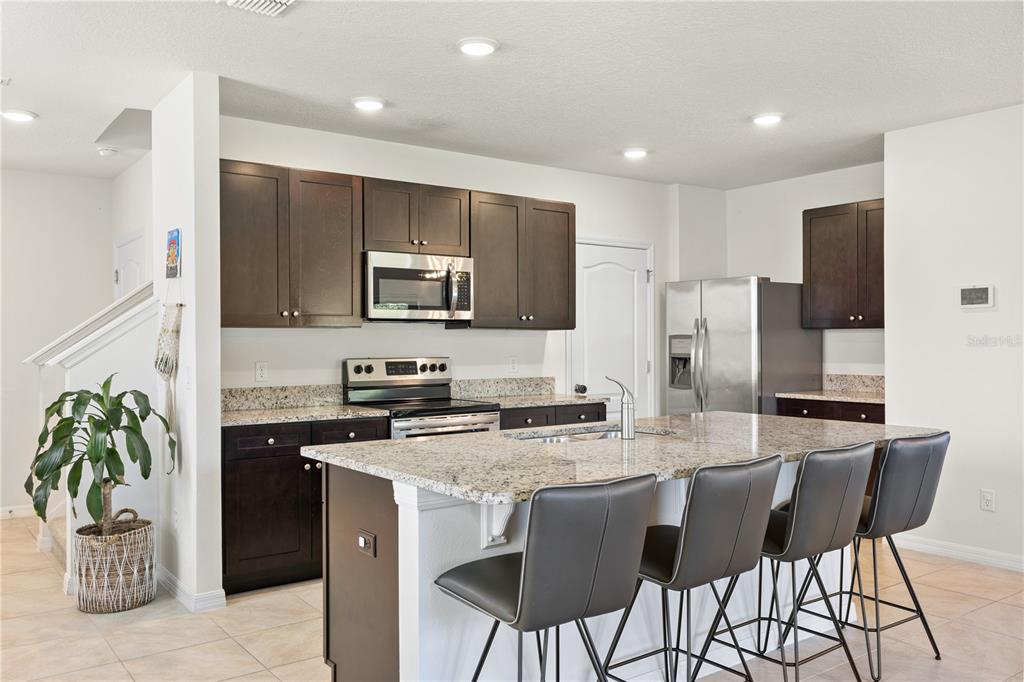 3090 Timber Hawk Circle Ocoee, FL 34761 - Photo 13 of 54 a kitchen with kitchen island granite countertop a stove a sink a refrigerator a dining table and chairs