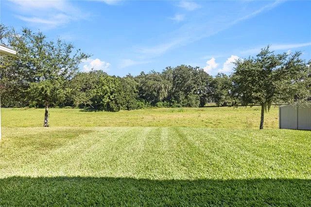 a view of a big house with a big yard and large trees
