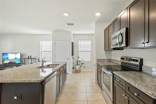 a large kitchen with cabinets chairs and stainless steel appliances