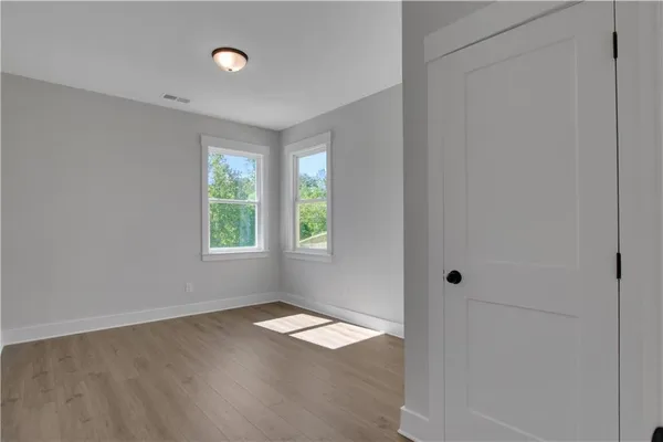 an empty room with wooden floor and windows