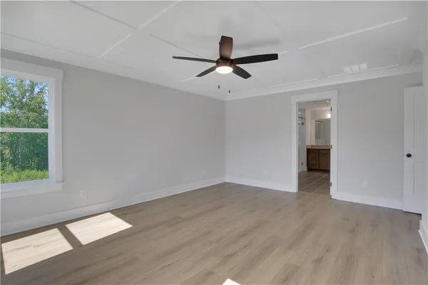 a view of empty room with wooden floor and fan