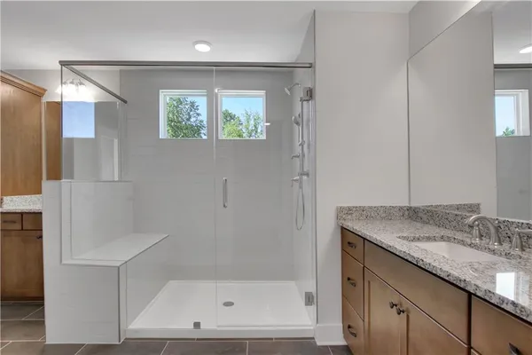 a bathroom with a granite countertop sink a mirror and shower