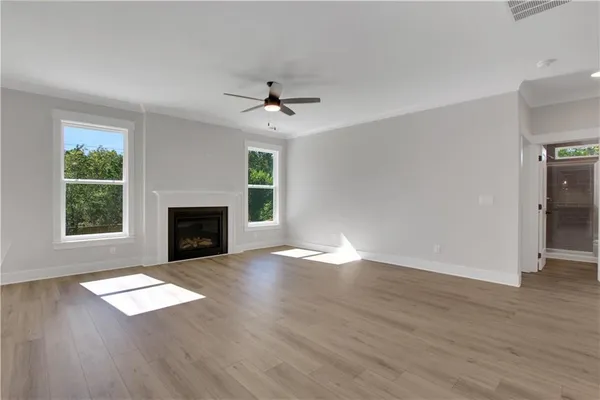 an empty room with wooden floor fireplace and windows