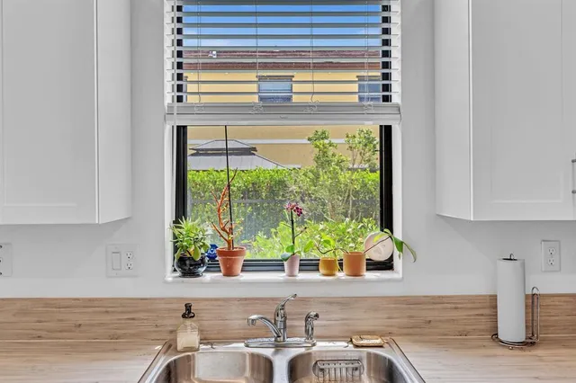 a kitchen with stainless steel appliances white cabinets a sink and a window