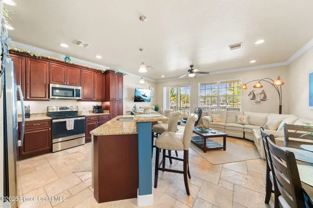 a kitchen with stainless steel appliances kitchen island granite countertop a stove a refrigerator a kitchen island a couches and chairs