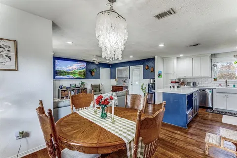 a view of a dining room with furniture a kitchen and chandelier