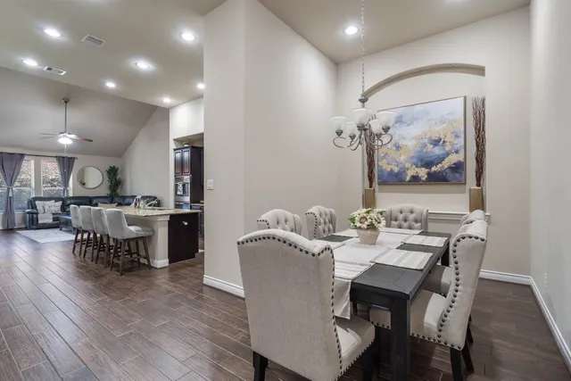 a large kitchen with cabinets chairs and wooden floor