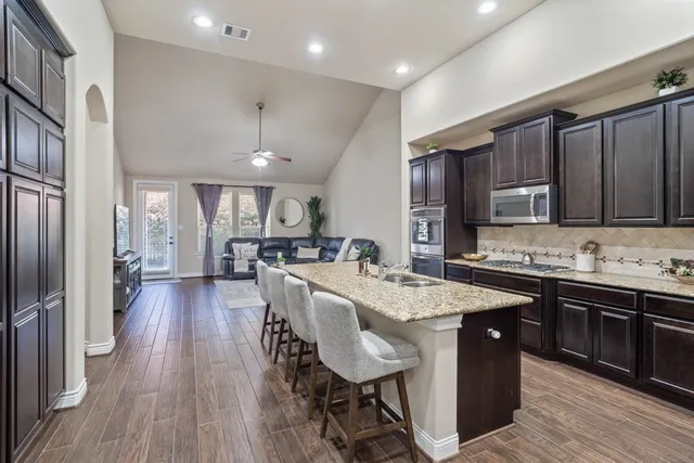a kitchen with granite countertop a table chairs microwave and refrigerator