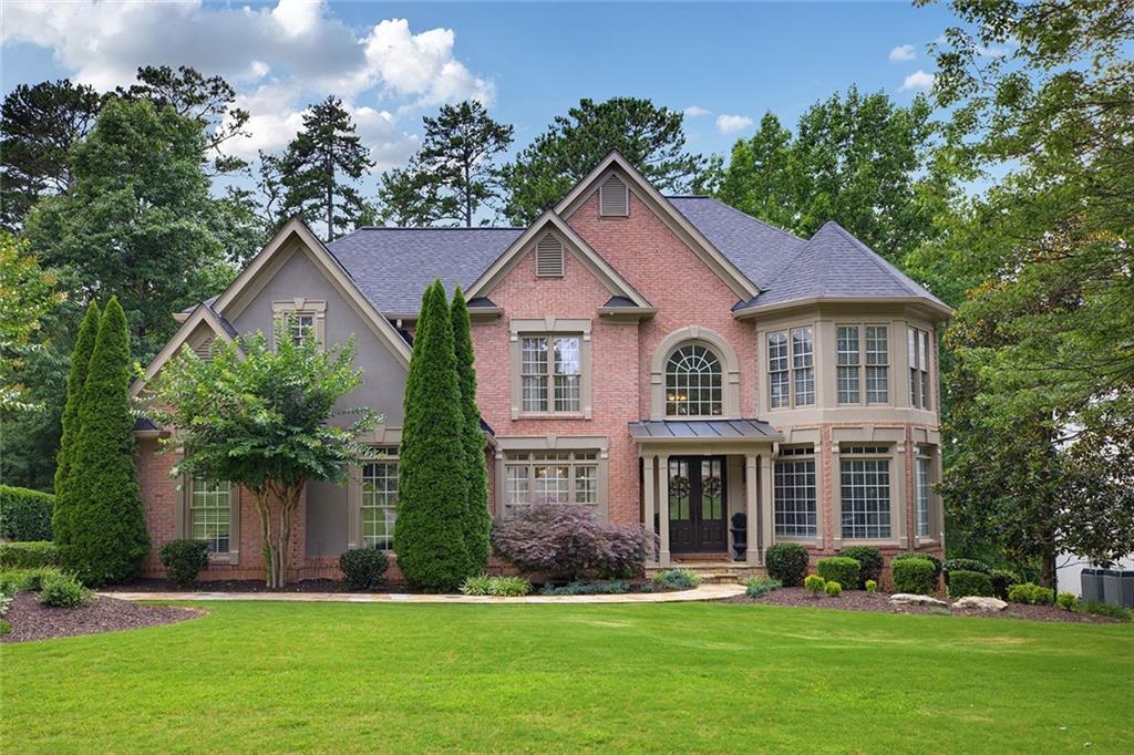 a front view of a house with garden and trees