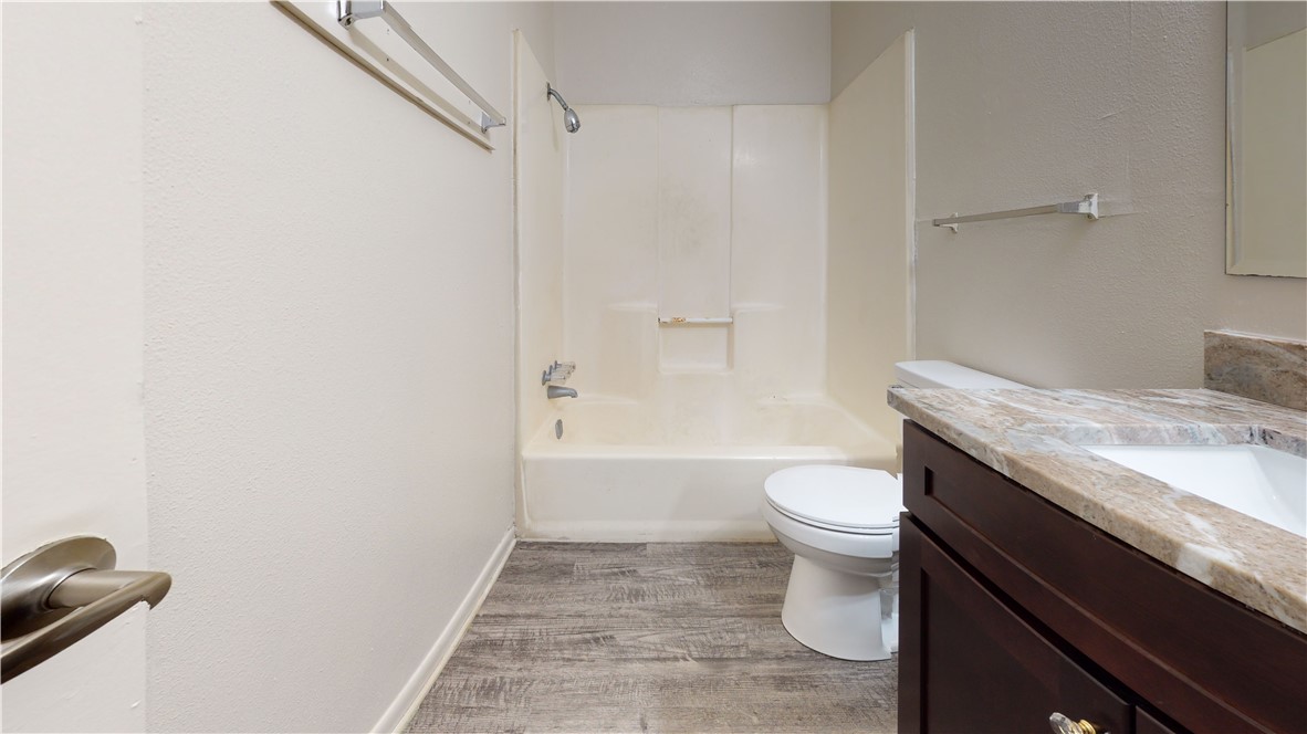 725 Peppertree Drive, Unit 23 Bryan, TX 77801 - Photo 10 of 16 Full bathroom featuring vanity, bathing tub / shower combination, a textured wall, and light wood-style floors
