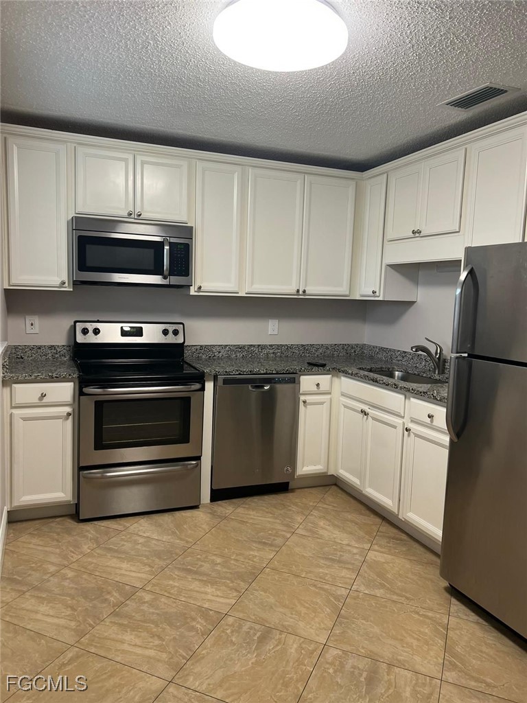 3325 Airport Road North, Unit T6 Naples, FL 34105 - Photo 4 of 13 a kitchen with granite countertop a stove top oven microwave and cabinets