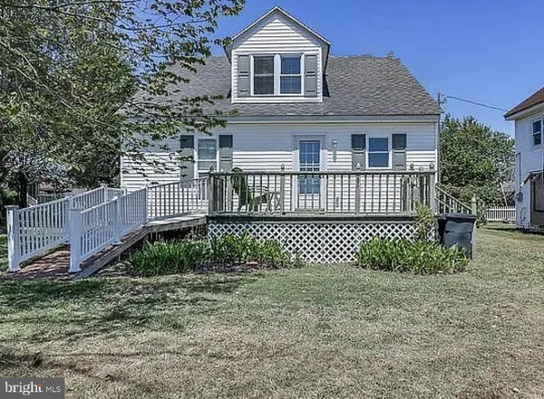 a white house that has a small yard and large trees