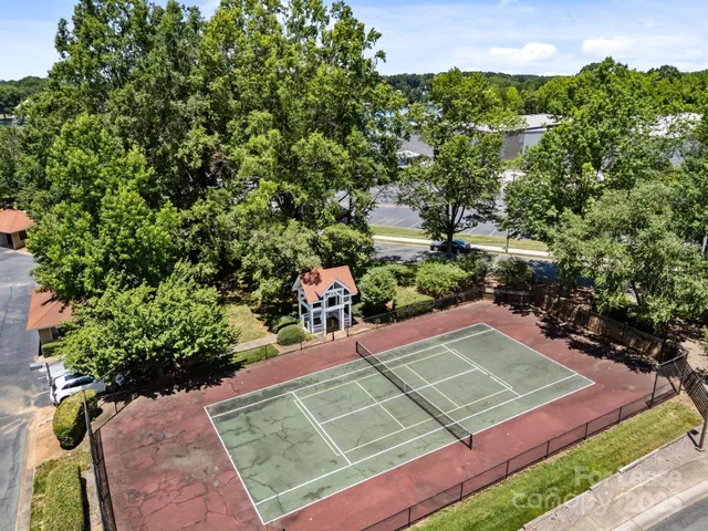 a view of a tennis ground with large trees