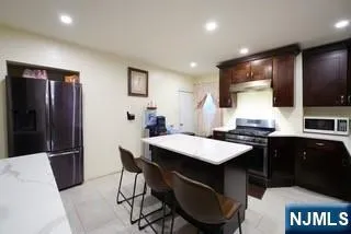 a kitchen with stainless steel appliances granite countertop a refrigerator a sink a stove a dining table and chairs