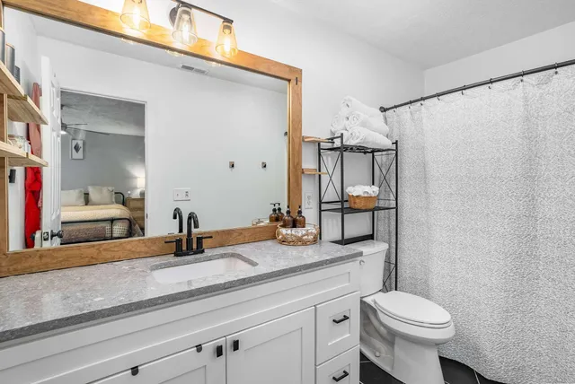 a bathroom with a granite countertop sink toilet and mirror