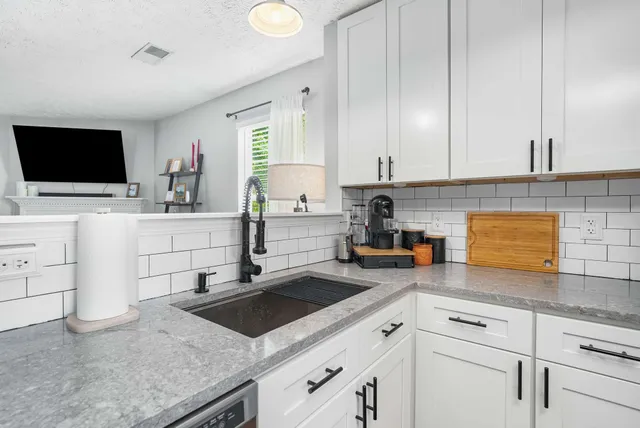 a kitchen with granite countertop a sink a stove and cabinets