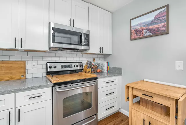 a kitchen with stainless steel appliances granite countertop white cabinets and a stove a oven with granite countertops