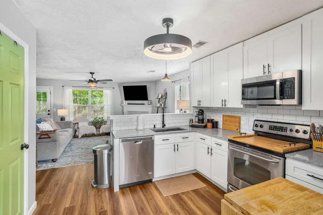 a kitchen with stainless steel appliances a stove a sink dishwasher a microwave oven with cabinets and wooden floor