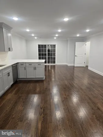 a large white kitchen with wooden floor and a window