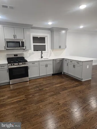 a large kitchen with cabinets wooden floor and stainless steel appliances