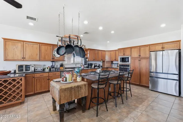 a kitchen with stainless steel appliances kitchen island granite countertop a table chairs and a refrigerator