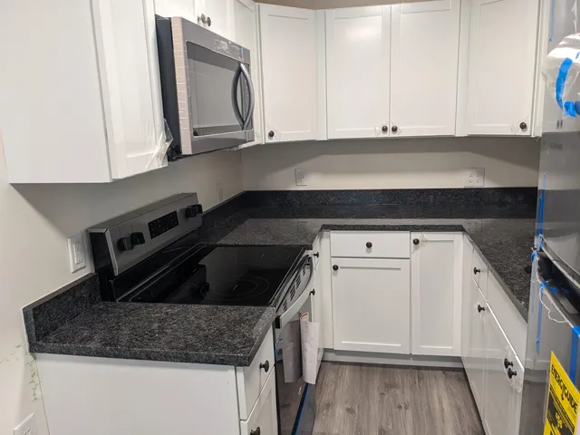 a kitchen with granite countertop white cabinets and a stove