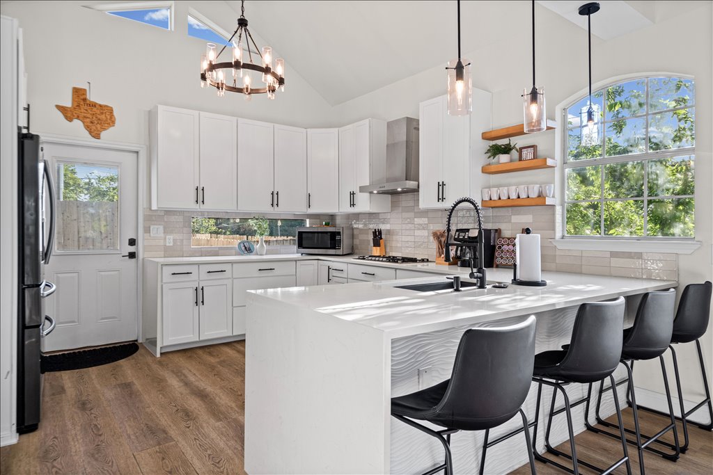 1201 Garden Street, Unit A Austin, TX 78702 - Photo 9 of 30 Bright, modern kitchen with vaulted ceilings and a waterfall-edge island, perfect for casual dining.